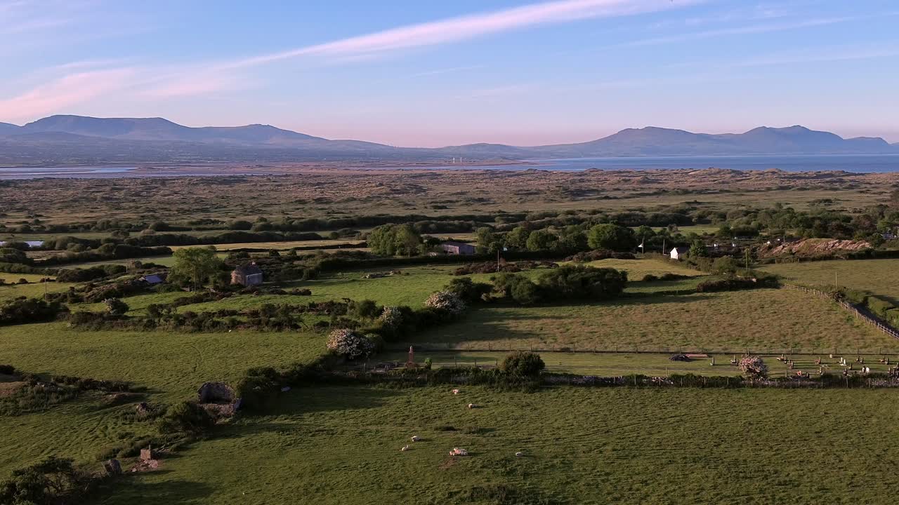 Idyllic Welsh meadow under Snowdonia mountains aerial orbiting view across rural Eryri national park
