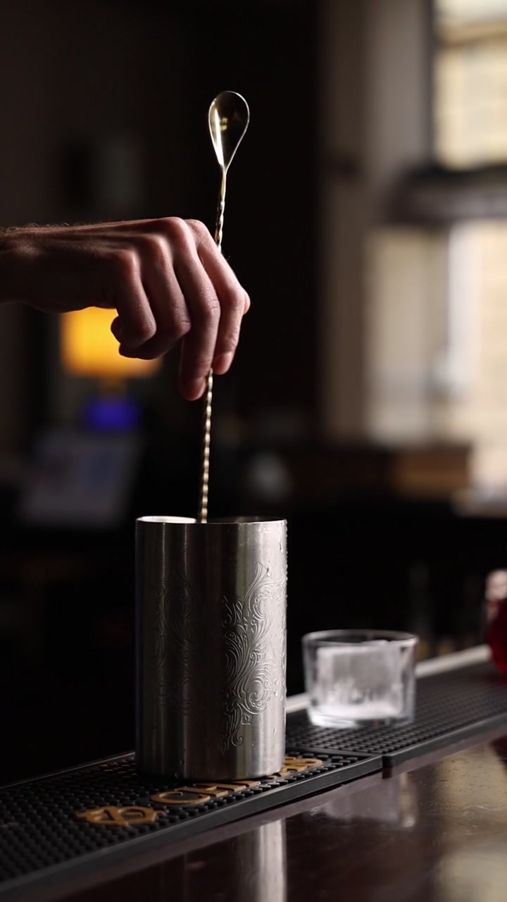 Bartender rører en cocktail i et metalrøreglas