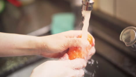 zeitlupenaufnahme weiblicher hände, die einige karotten unter wasser aus einem küchenhahn waschen