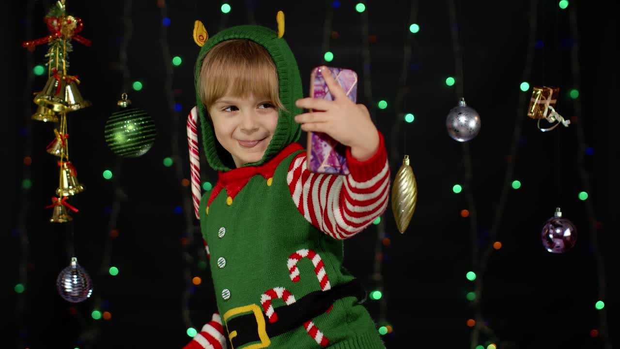 niña con disfraz de ayudante de santa claus haciendo selfies en el teléfono móvil. fiestas de año nuevo
