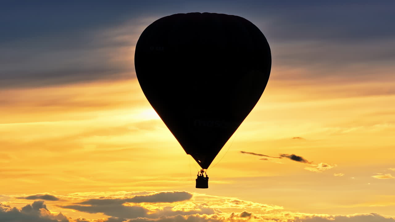 Vista aerea da drone di una mongolfiera che vola sopra le nuvole al tramonto