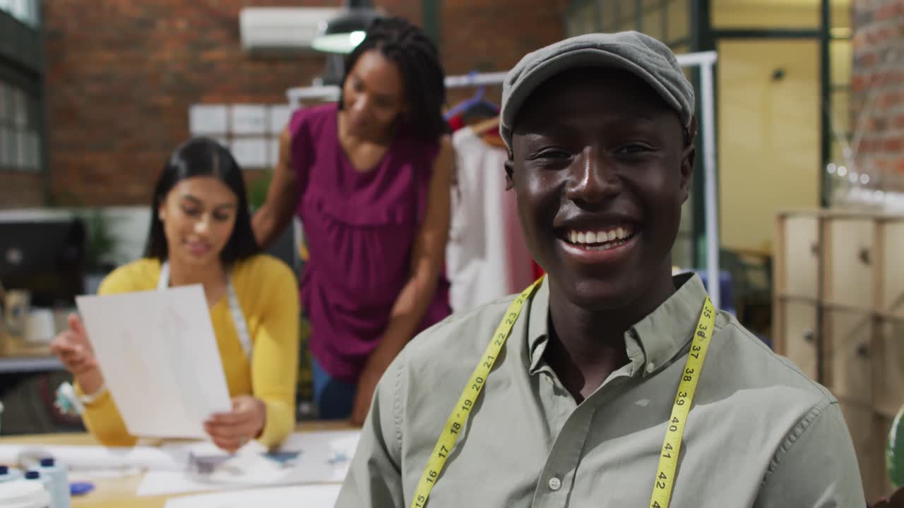 Ritratto di felice stilista di moda uomo afroamericano con metro da sarto in ufficio.