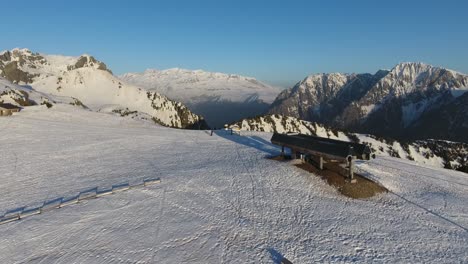 ski lift station at chamrousse mountain summit in the french alps during sunset, aerial flyover approach shot