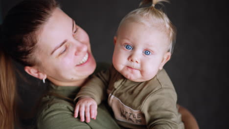 Sweet little Caucasian baby boy's face with blue eyes. Woman is holding her beloved son. Close up.