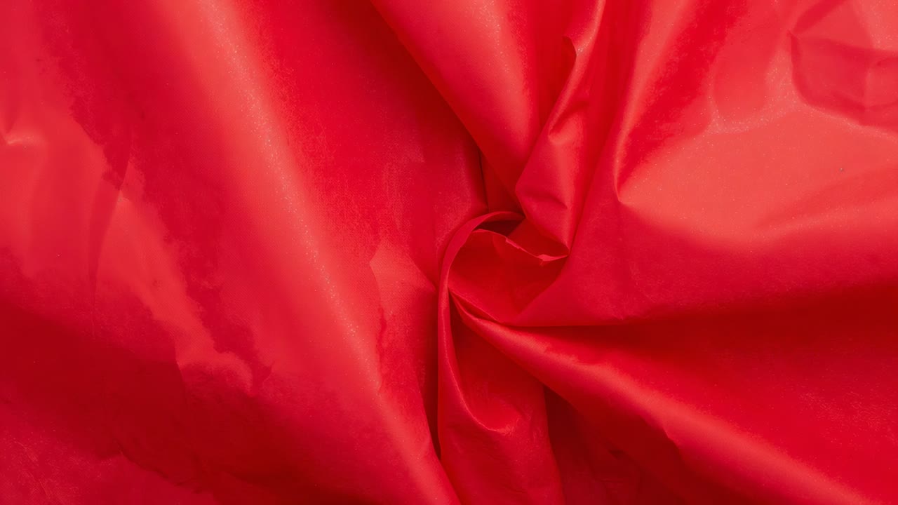 Settling after movement swirled red fabric twisting and folds moving in closeup with glints sliding