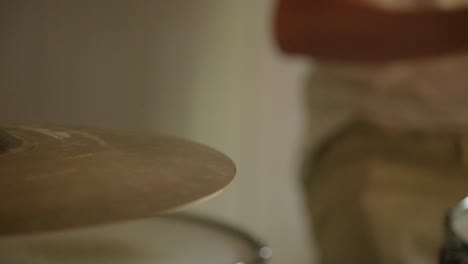 Drummer-practicing-rudiments-on-the-ride-cymbal-and-surrounding-kit-with-beautiful-natural-light-coming-the-window