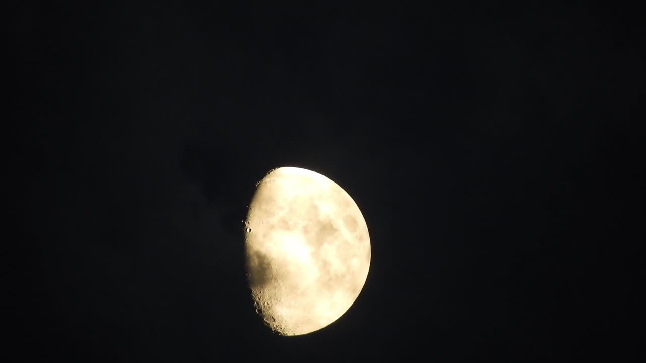 Moon at night with cloud real time. 4k video moon in the black sky.  Clouds passing by moon at night. night sky with cloudy weather