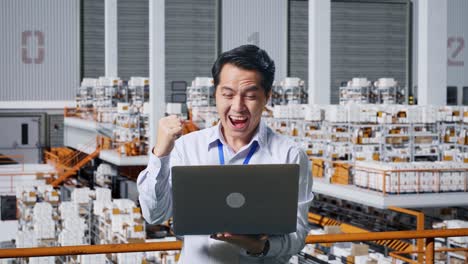 empleado del almacén celebrando el éxito con una computadora portátil