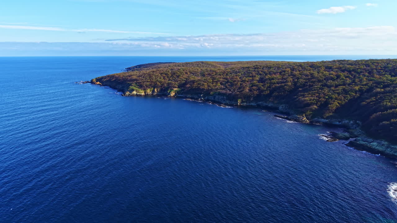 Acque blu vibranti abbracciano la costa frastagliata in una serena fuga sotto il cielo luminoso