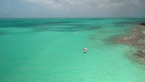 BOAT-WAIT-PEOPLE-KITESURF,-SALINAS-LOS-ROQUES-ARCHIPELAGO,-DRONE-SHOT