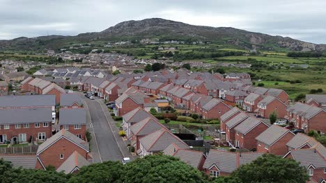aerial view circling modern red brick housing neighbourhood under holyhead mountain in wales