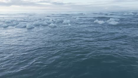 cracked ice floating on the wavy water of sea at diamond beach in iceland