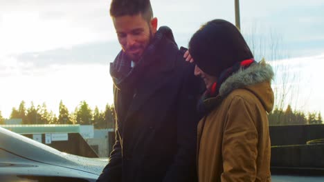 Couple-talking-while-charging-the-electric-car-on-a-winter-day