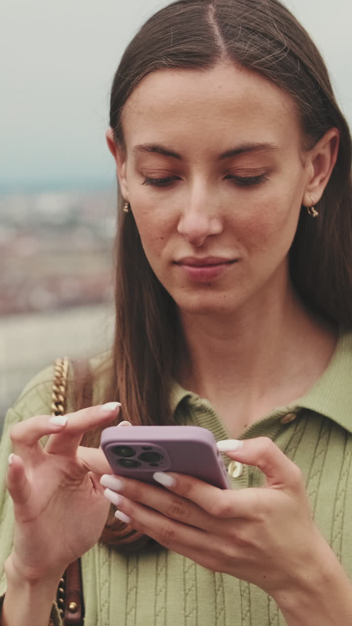 Giovane donna che scorre lo smartphone all'aperto con uno sfondo sfocato della città