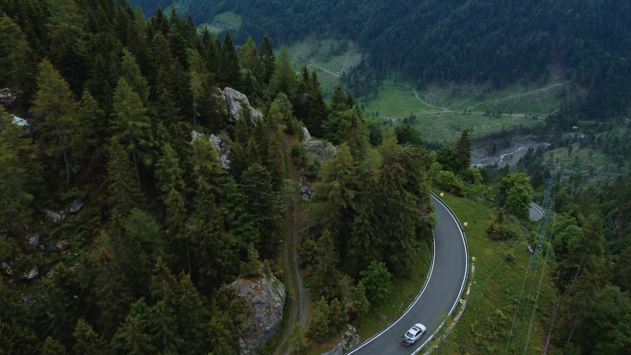volando a lo largo de un coche en la idílica carretera serpentina de montaña plöckenpass en los alpes austriacos e italianos naturales en verano con árboles verdes y coches en la calle