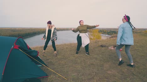 young women dance spending time at campsite on green hill