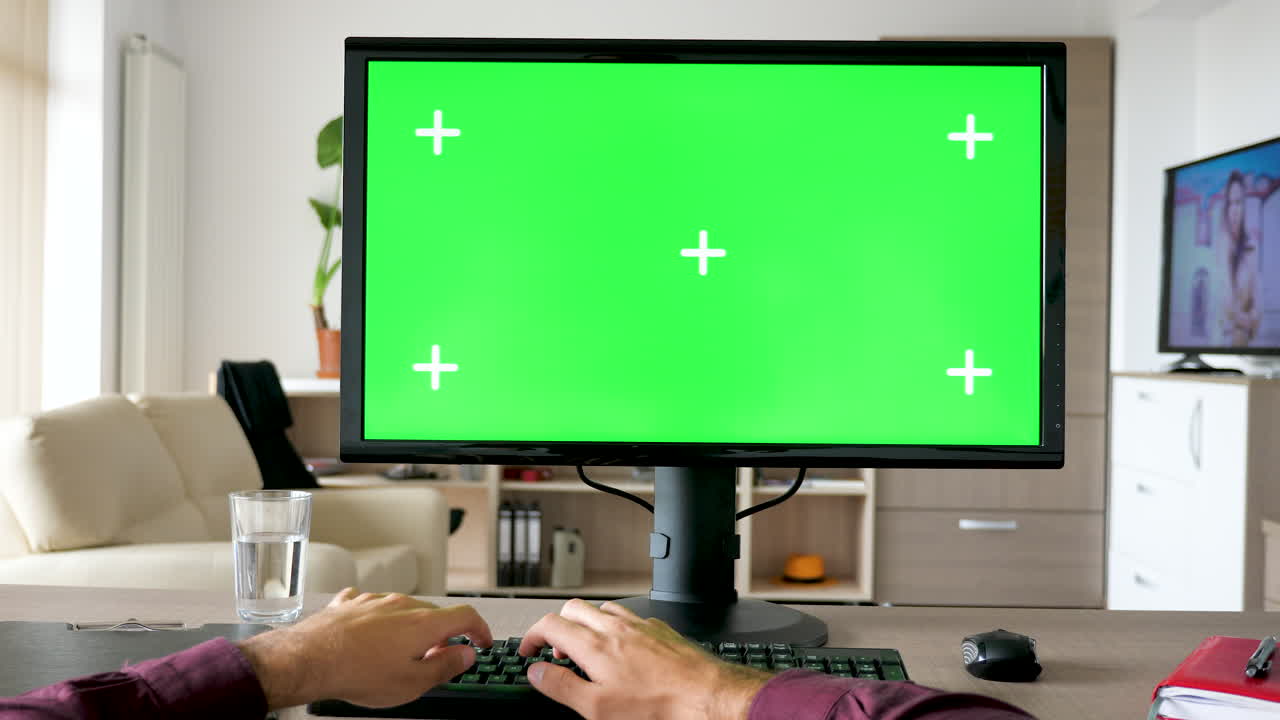 Man working on computer with green screen monitor