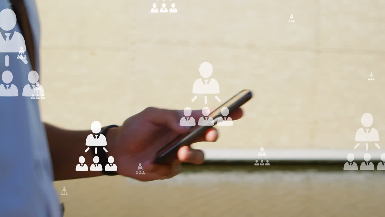 animación de iconos de usuario sobre las manos de un hombre biracial que usa un teléfono inteligente en la ciudad