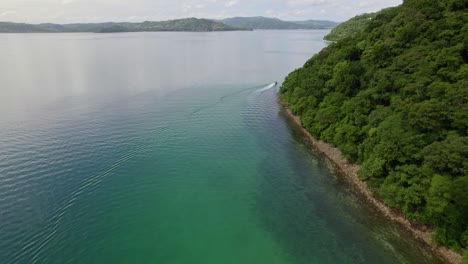 Aerial-dolly-in-of-turquoise-sea-and-green-dense-rainforest-hillside-in-Nacascolo-beach-on-a-cloudy-day,-Papagayo-Peninsula,-Costa-Rica