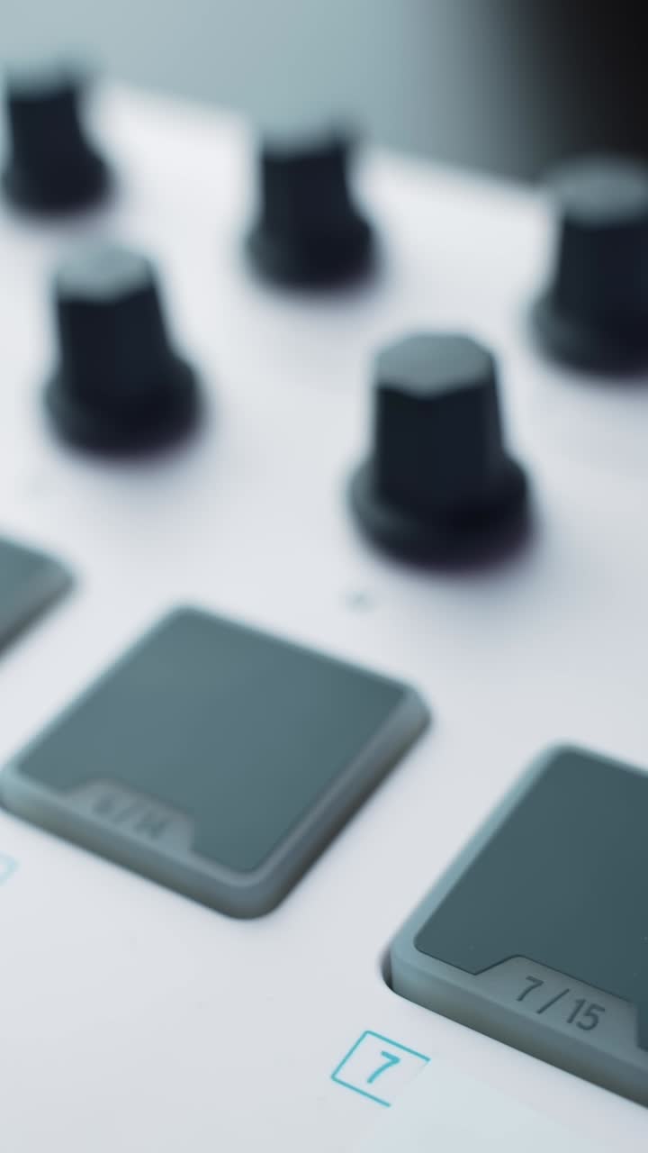 Vertical macro shot of MIDI controller pads and knobs with rack focus, clean studio gear aesthetic for music production and sound design