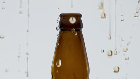 golden beer splashing bottle after opening in super slow motion close up.