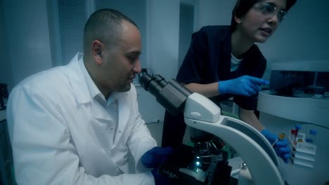 profesionales médicos que utilizan microscopio y equipos de laboratorio