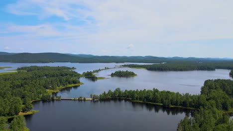 Panning-drone-shot-of-islands-in-an-Adirondack-lake-surrounded-by-mountains