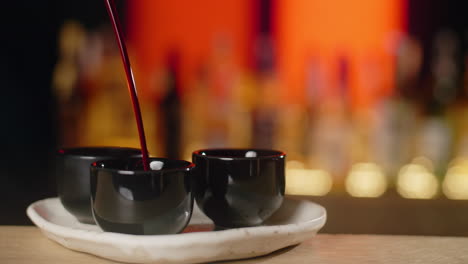 pouring drinks into small glasses at a bar
