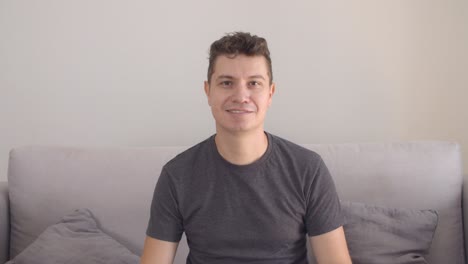 Happy-handsome-man-wearing-casual-t-shirt,-sitting-on-couch