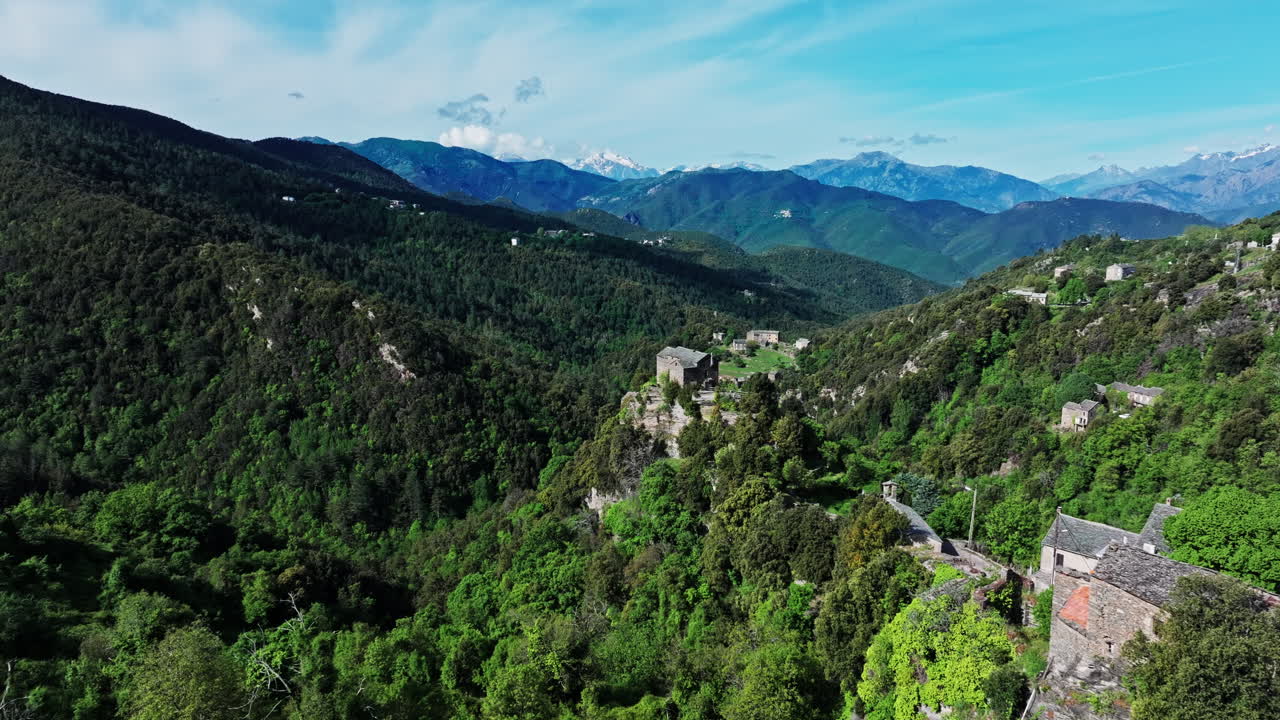 Aerial drone shot over the green lush landscape of inland Corsica, France. High view of the landscape and the mountains in the distance. Summer holidays destination for hikers and mountain lovers