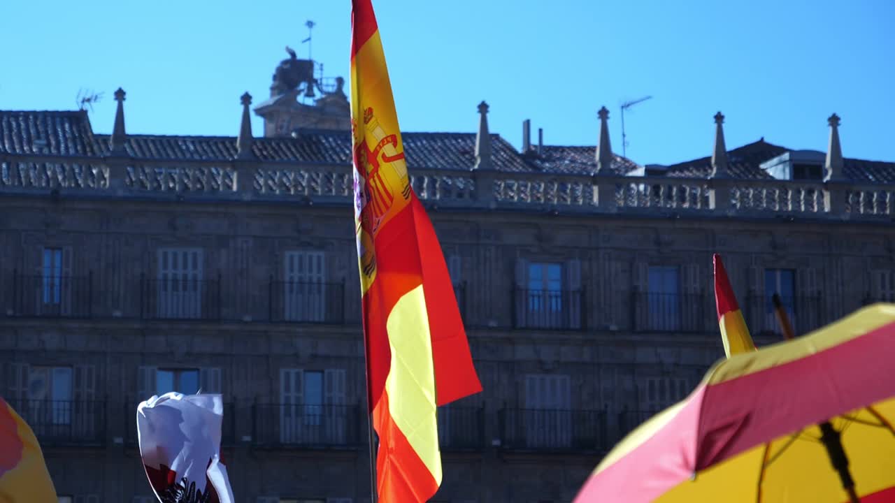 Espanjan lippu liehuu tuulessa historiallista rakennusta vasten.