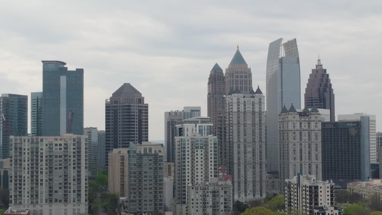 Aerial camera rising shot of the downtown Atlanta, Ga. cityscape skyline with iconic skyscraper buildings moving up from Piedmont Park waterfront and rising up to the top of the buildings.