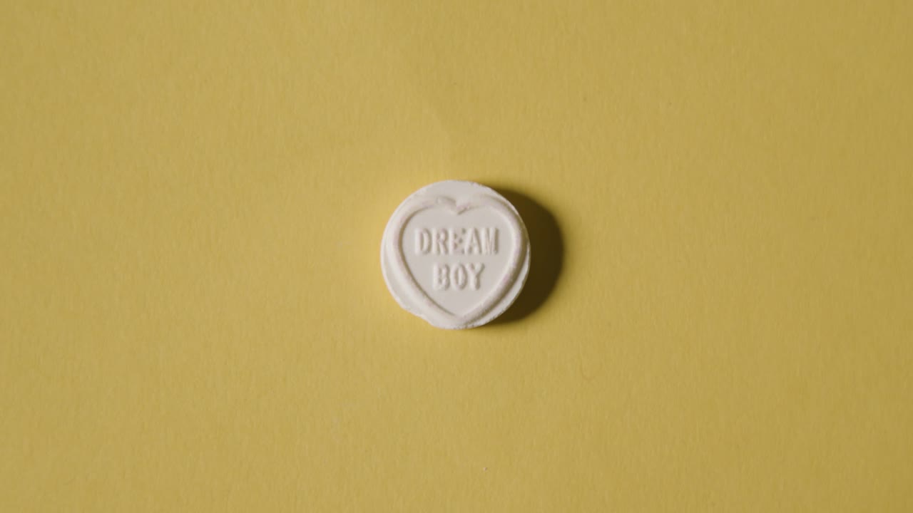 노란색 배경에 꿈의 소년 메시지와 함께 심장 사탕을 손에 들고