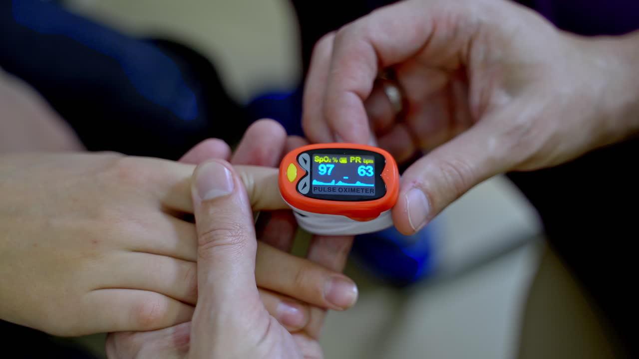 Special device for measuring heart rate. Doctor puts electrical appliance on boys finger. Selective focus.