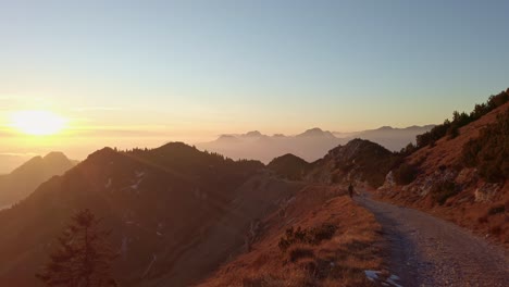 someone is walking down a beautiful mountain path, the sun is setting, colors are warm