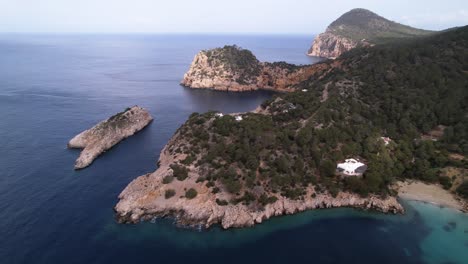 Wunderschöne-Naturlandschaft-Der-Klippen-Und-Des-Ozeans-Von-Ibiza,-Bäume-Füllen-Den-Berghang---Gleitende-Luftaufnahme