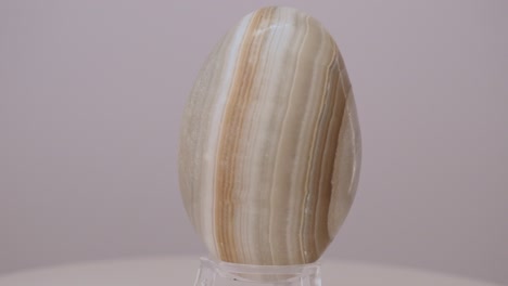 huevo mineral de ónix de color claro girando lentamente en una mesa giratoria