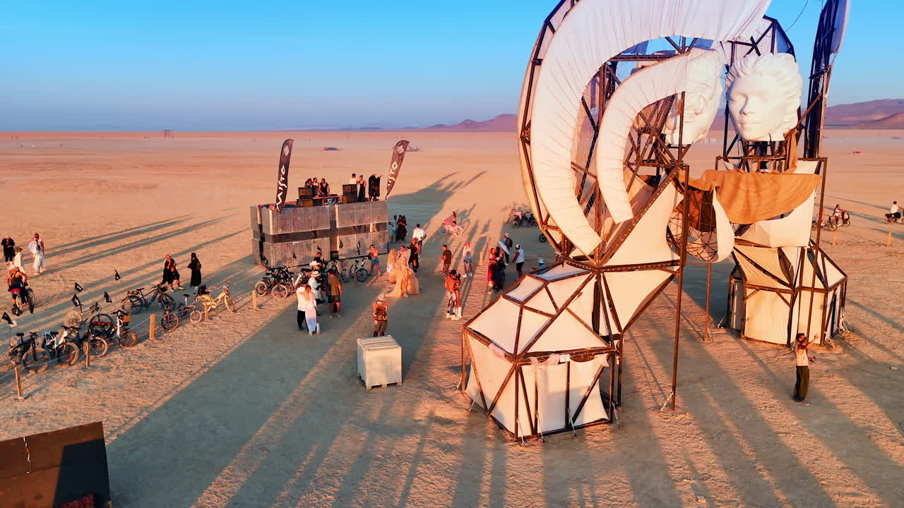 Nevada, USA, 22 August 2025: Symbolic Burning Man structure with people in desert. Visitors walk and cycle around symbolic art installations in the desert at Burning Man festival