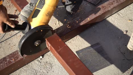 artesano que corta metal con una molienda de disco en el sitio de construcción de un edificio