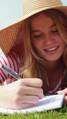 pretty young student lying on the grass studying