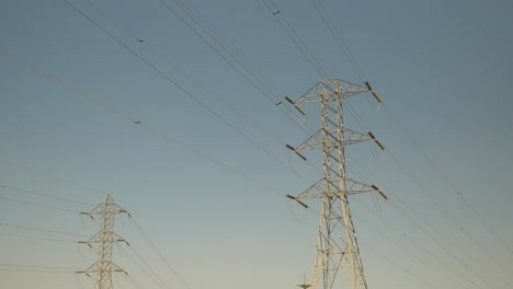 Two-electrical-transmission-towers-standing-in-front-of-a-blue-clear-sky-in-the-daytime