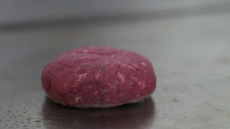 Raw-hamburger-patty-cooking-on-a-flat-restaurant-grill