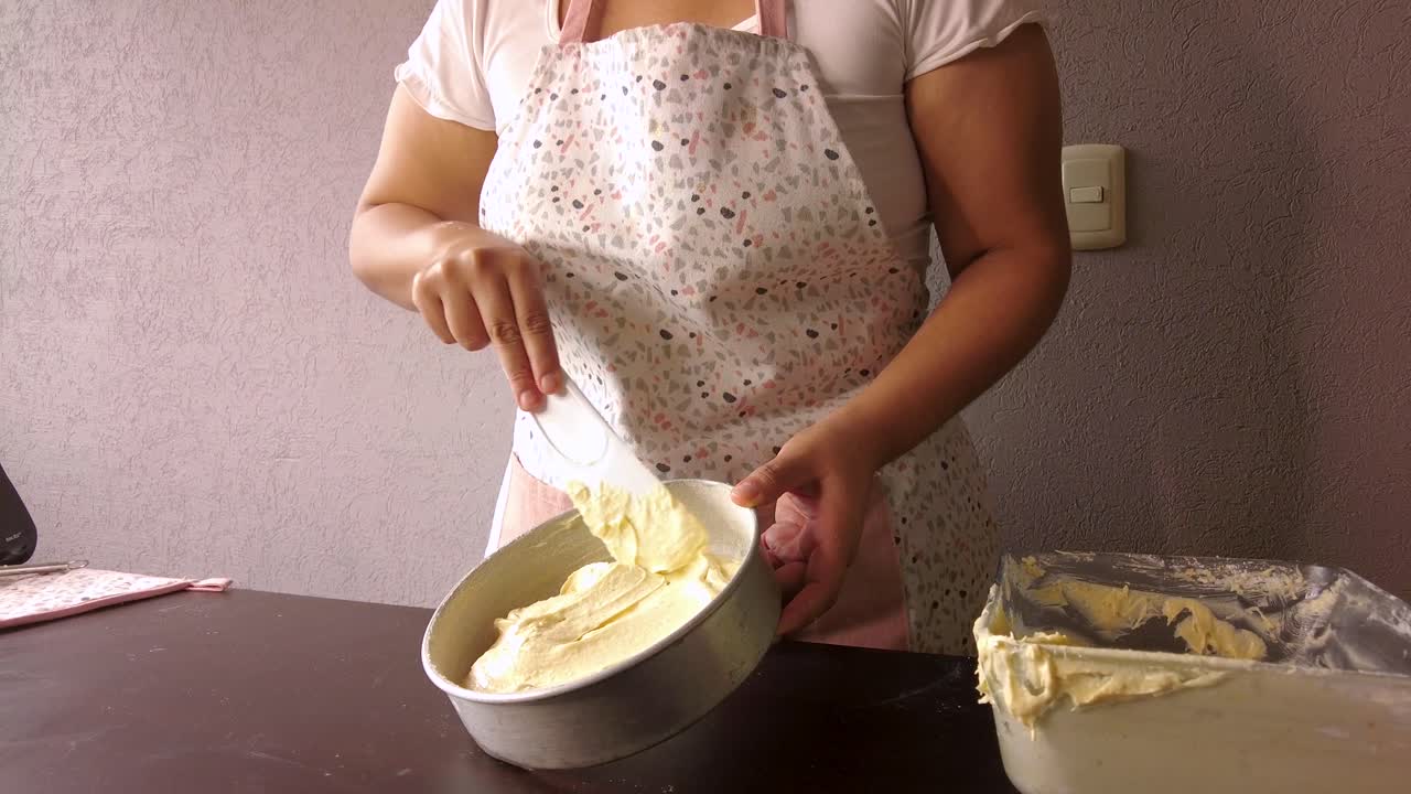 mujer latina con un delantal preparando la cocina horneando un pastel extendiendo el doug con un raspador