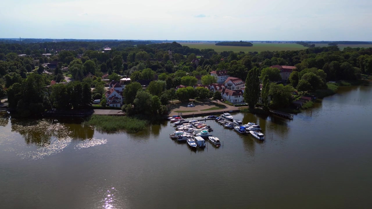 Fortøyd i en rolig havn, plassert ved siden av den pittoreske landsbyen Wustrau ved bredden av en fredelig innsjø, omgitt av grøntområder. Magisk luftfoto fra drone, filmet ovenfra.