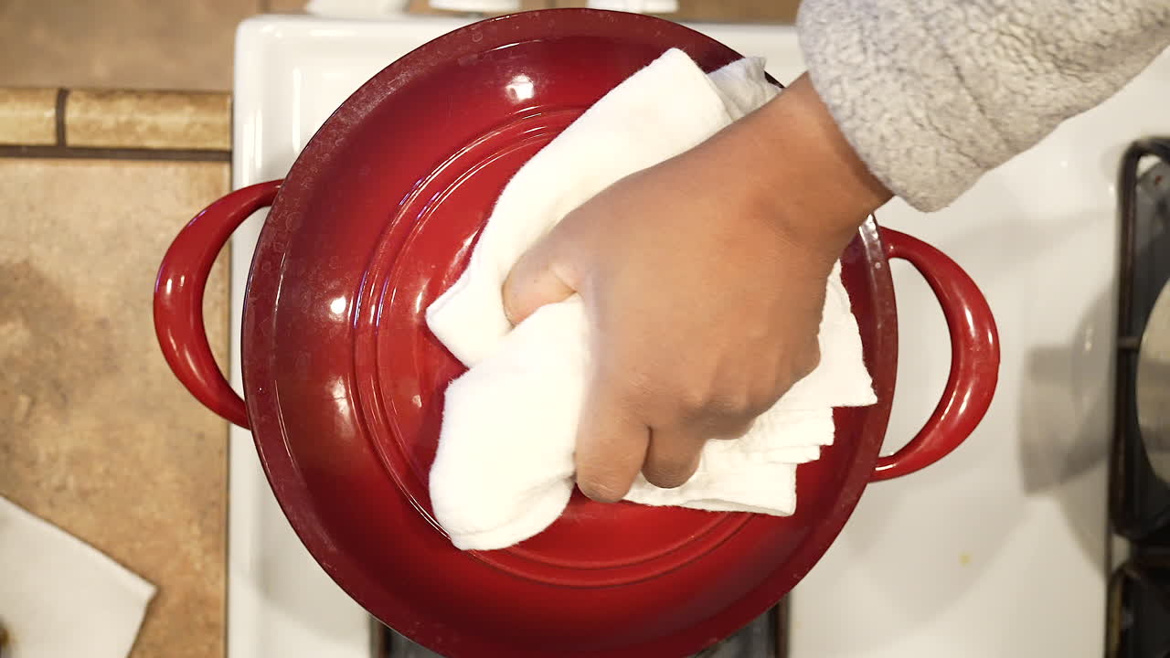 levantando la tapa de una olla caliente humeante de sopa de champiñones de arroz salvaje a fuego lento - vista superior de la serie de arroz salvaje