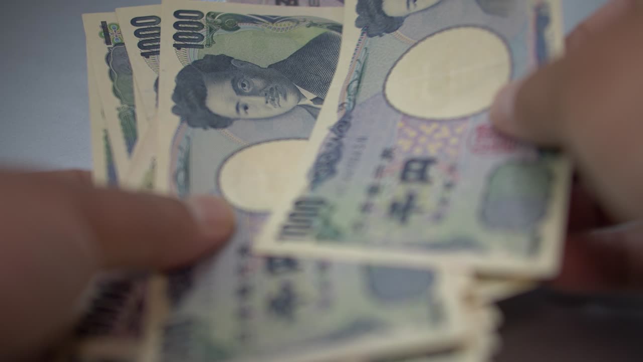 hombre contando el yen japonés en la mesa blanca