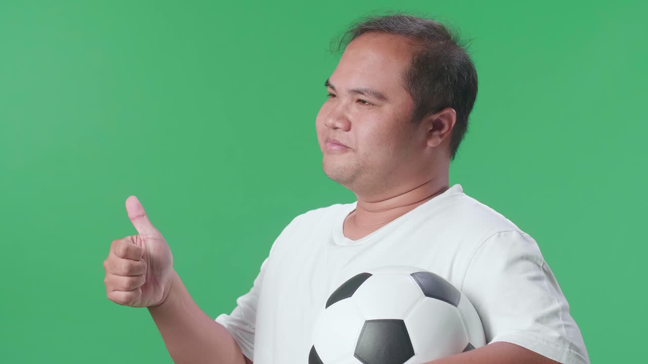 hombre sosteniendo una pelota de fútbol y dando un pulgar hacia arriba.