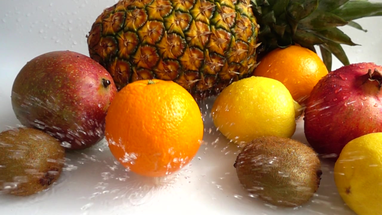 Caída de naranja sobre un fondo de frutas tropicales. Cámara lenta.