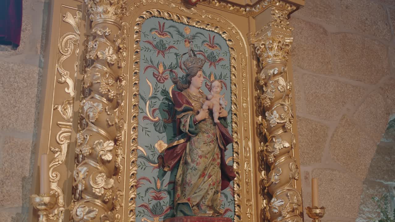 Close up of an intricately carved gilded altar featuring a sacred statue and floral patterns