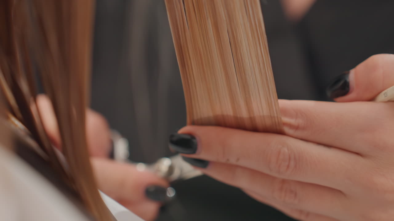 Nærbillede af vådt hår, der klippes med saks, energisk transformationsscene, sakse, der klipper spidser, sorte neglelakfingre, der holder lokkerne, kappe og salonbaggrund, fokus på ren linje